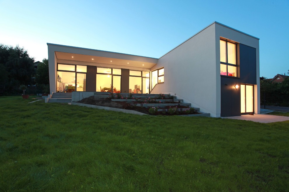 Источник вдохновения для домашнего уюта: двухэтажный, белый частный загородный дом среднего размера в стиле модернизм с облицовкой из цементной штукатурки и плоской крышей