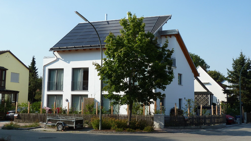 Modelo de fachada blanca minimalista de tamaño medio de tres plantas con revestimiento de estuco y tejado de un solo tendido