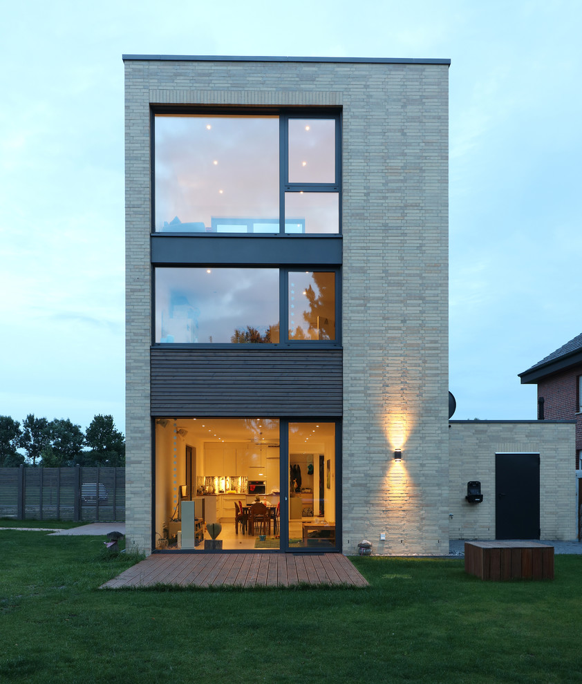 Ejemplo de fachada de casa beige minimalista grande de tres plantas con revestimiento de ladrillo y tejado plano