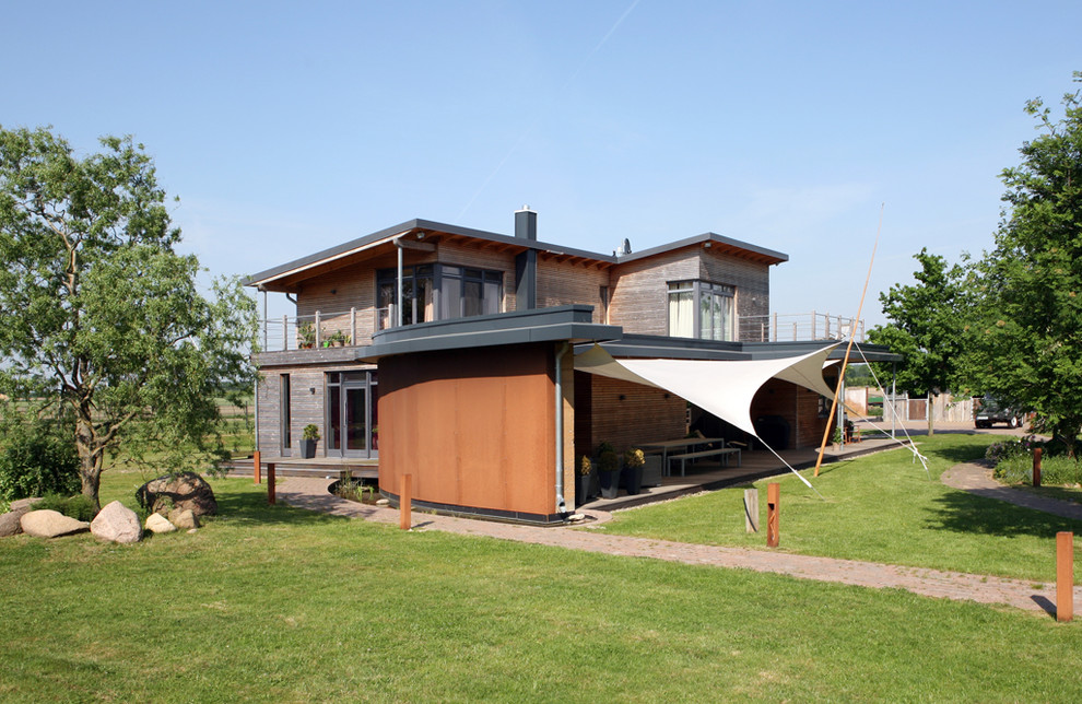 Brown and medium sized contemporary two floor house exterior in Hamburg with wood cladding and a lean-to roof.