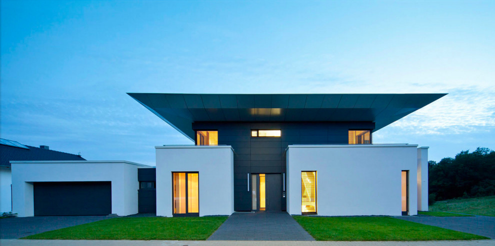 Cette image montre une grande façade de maison noire design à un étage avec un revêtement mixte et un toit plat.