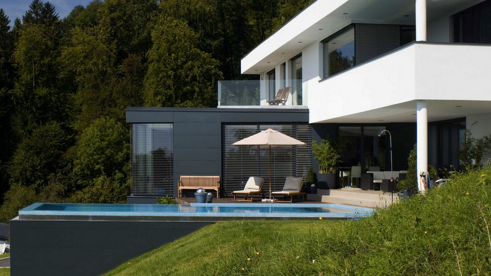 Cette image montre une grande façade de maison grise minimaliste à un étage avec un toit plat.