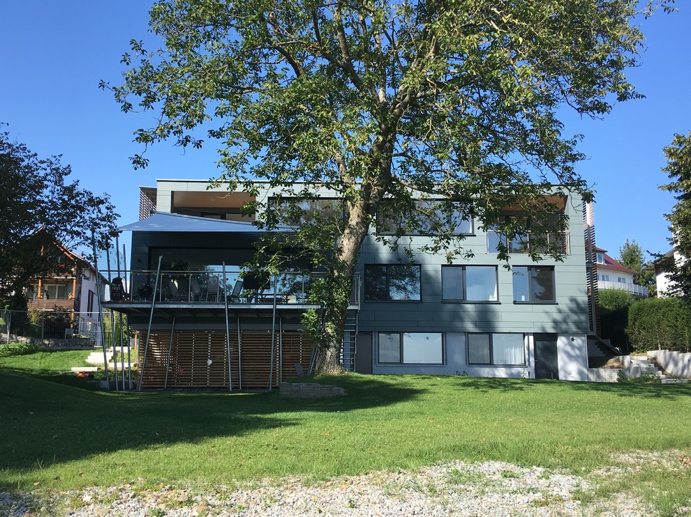 Imagen de fachada gris contemporánea de tres plantas con revestimiento de aglomerado de cemento y tejado plano