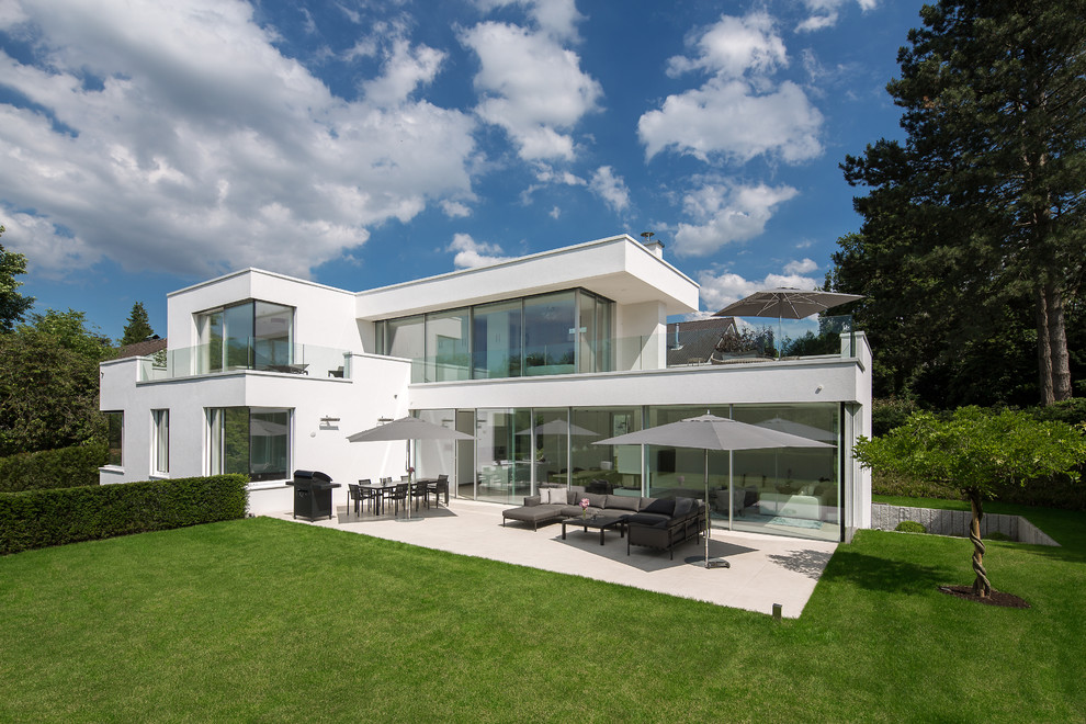 Diseño de fachada blanca actual de dos plantas con tejado plano y revestimiento de estuco