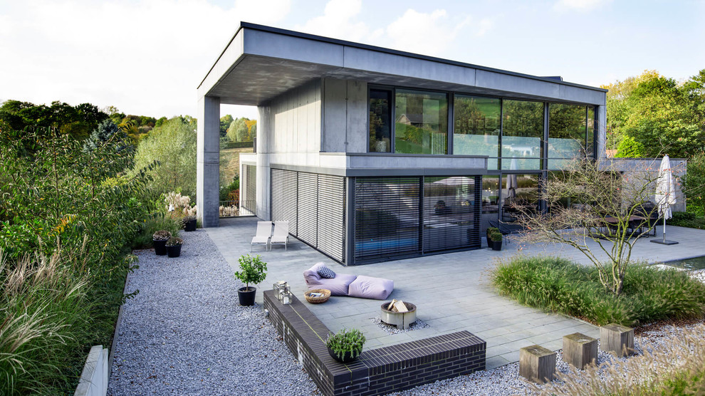 Inspiration för ett stort funkis grått hus, med två våningar, platt tak och tak i metall