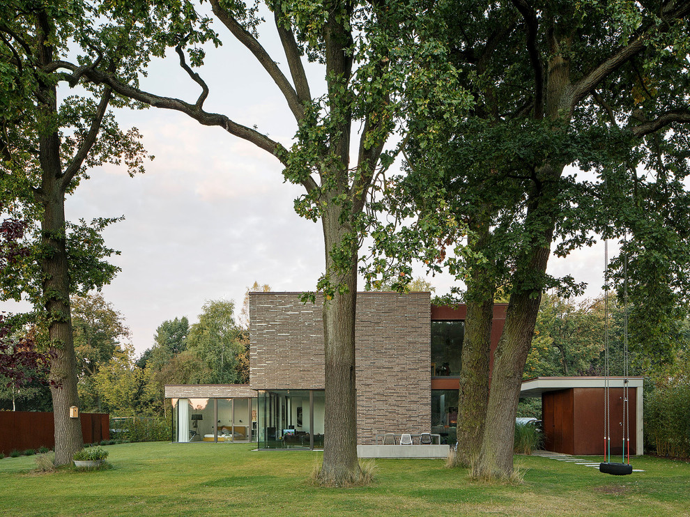 Diseño de fachada de casa contemporánea grande de dos plantas con revestimientos combinados y tejado plano