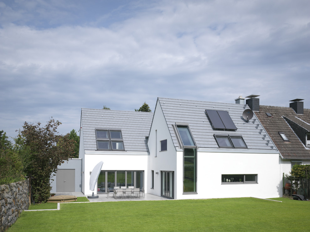 Inspiration pour une façade de maison blanche design de taille moyenne et à un étage avec un toit à deux pans.