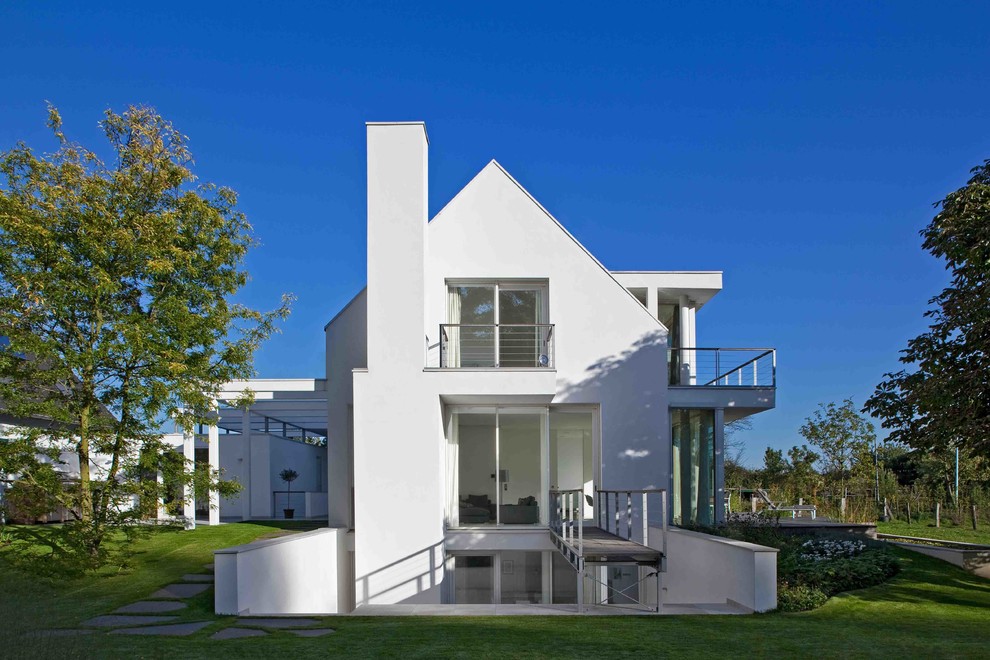 Inspiration pour une grande façade de maison blanche design en stuc à un étage avec un toit à deux pans.