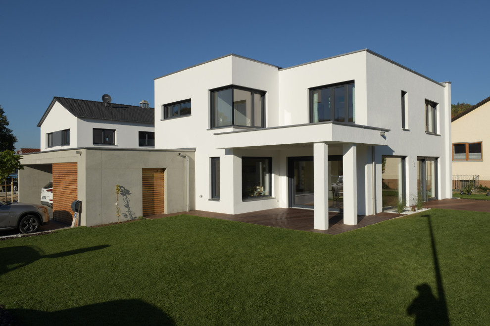 Idée de décoration pour une façade de maison blanche design en pierre de taille moyenne et à un étage avec un toit plat et un toit végétal.