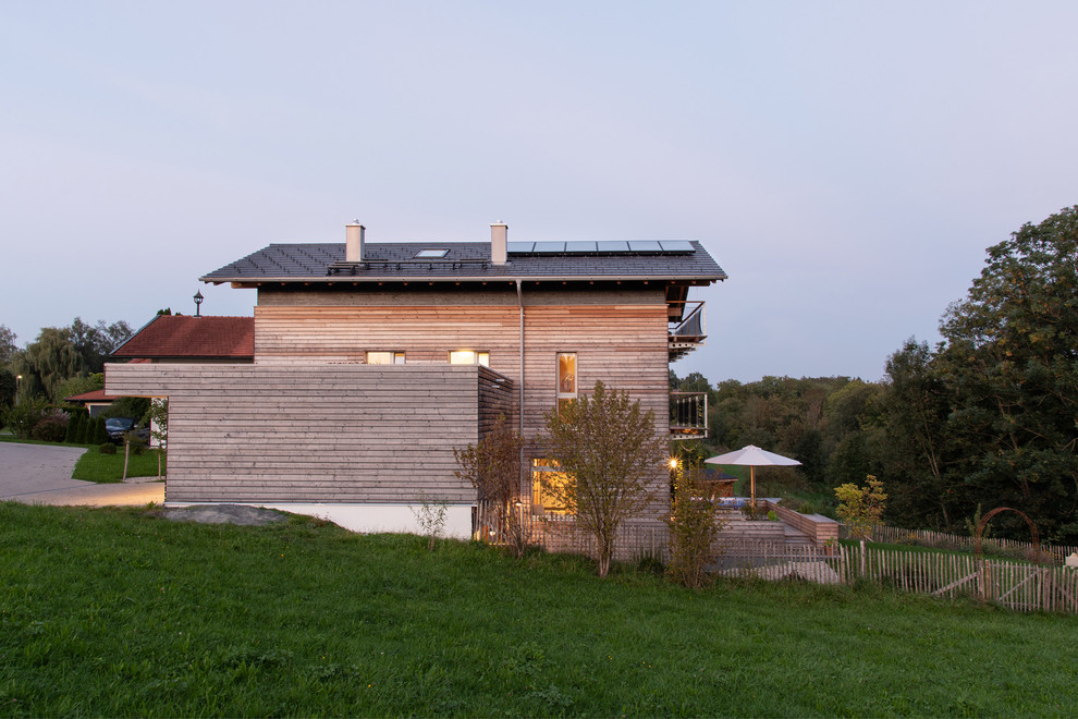 На фото: деревянный частный загородный дом среднего размера в скандинавском стиле с разными уровнями, двускатной крышей и черепичной крышей