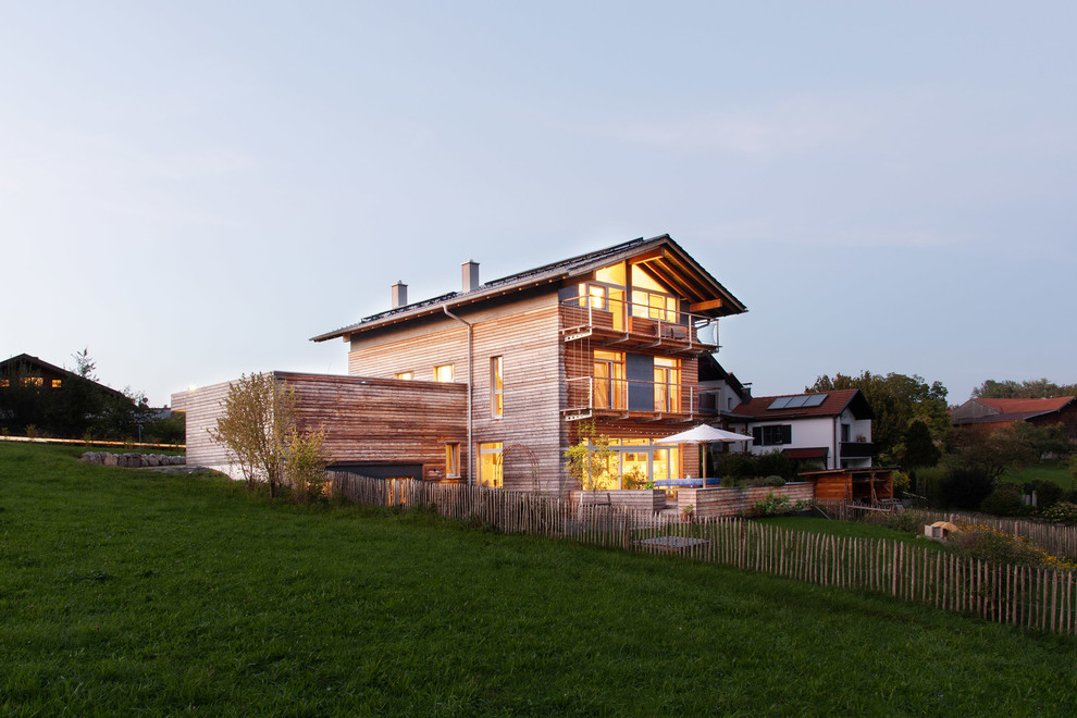 Diseño de fachada de casa gris nórdica de tamaño medio a niveles con revestimiento de madera, tejado a dos aguas y tejado de teja de barro