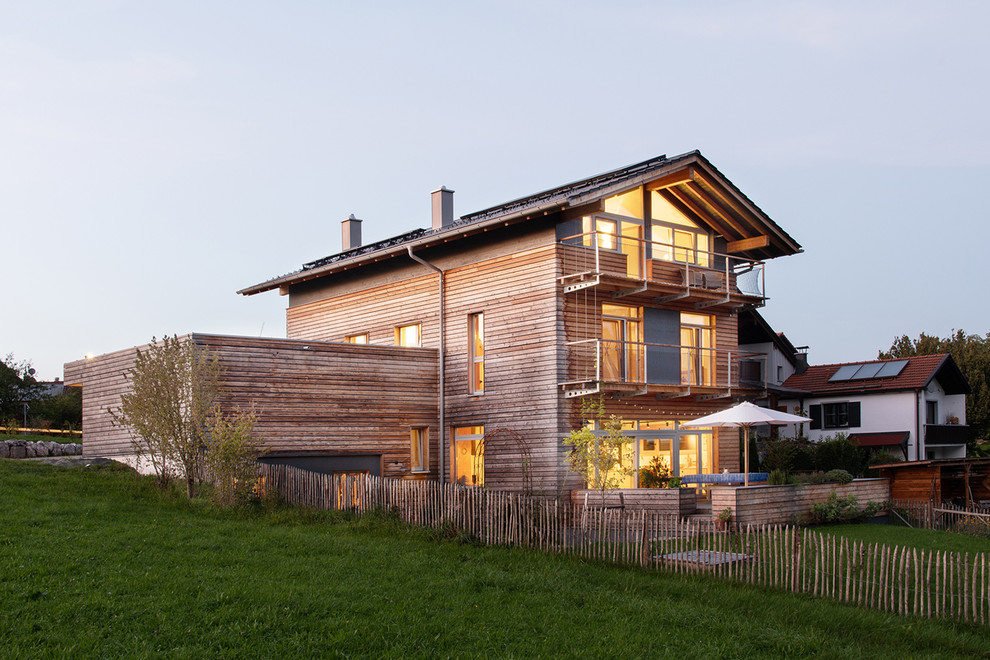 Идея дизайна: деревянный, двухэтажный, коричневый частный загородный дом среднего размера в скандинавском стиле с двускатной крышей и черепичной крышей