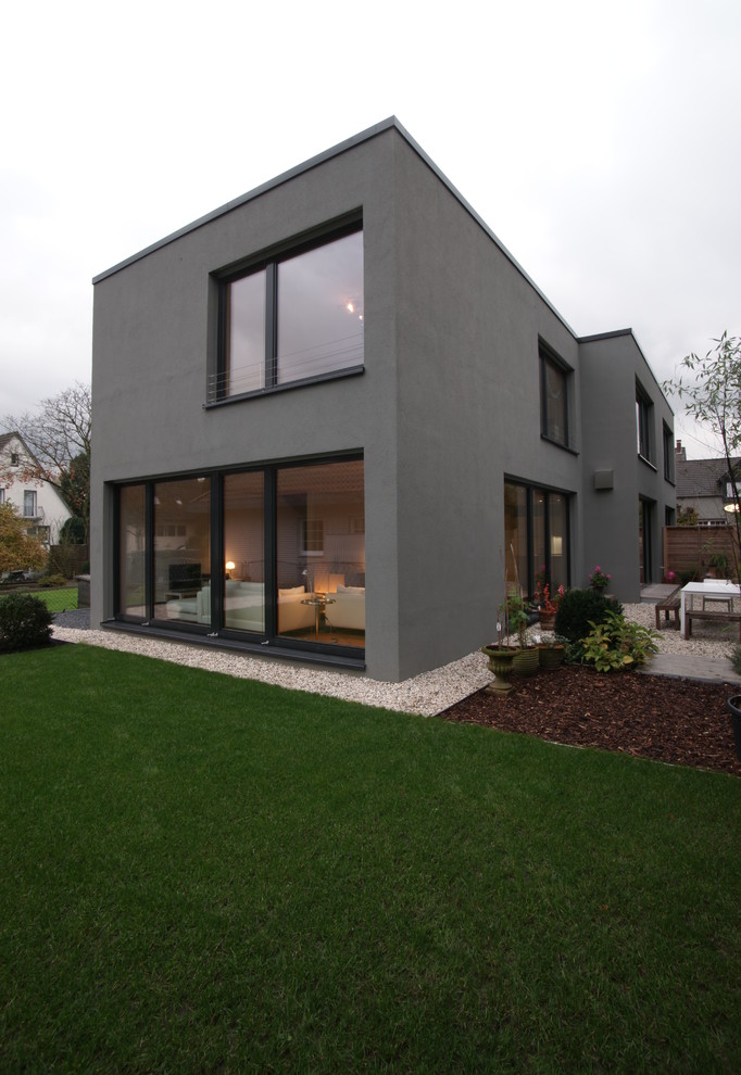 Réalisation d'une petite façade de maison grise design en stuc à un étage avec un toit plat.