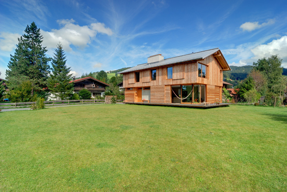Réalisation d'une façade de maison marron champêtre en bois de taille moyenne et à un étage avec un toit à deux pans.