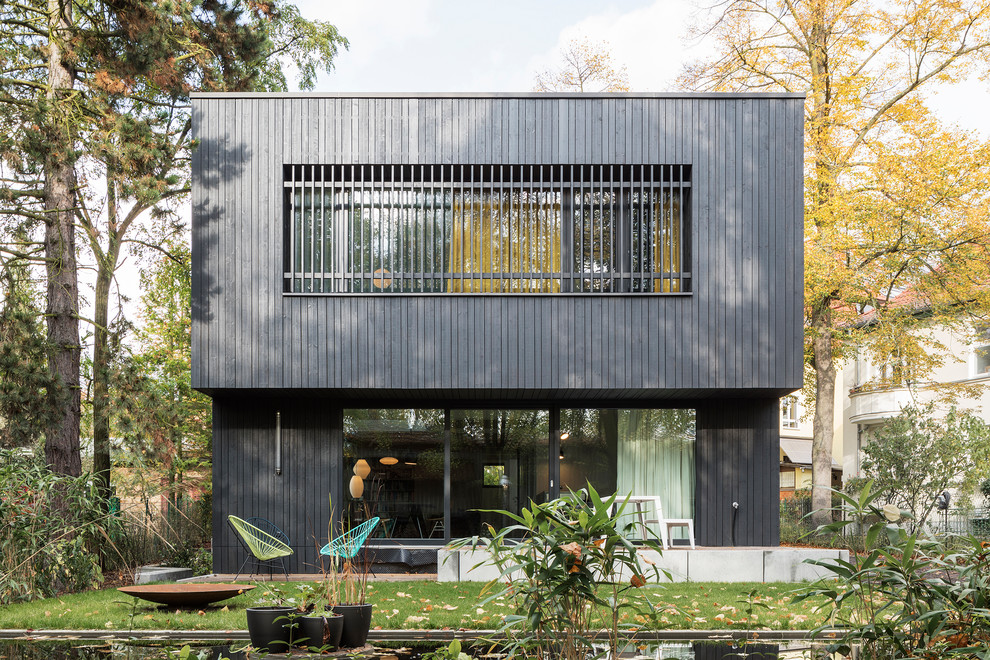 Ispirazione per la facciata di una casa nera contemporanea a due piani di medie dimensioni con rivestimento in legno e tetto piano