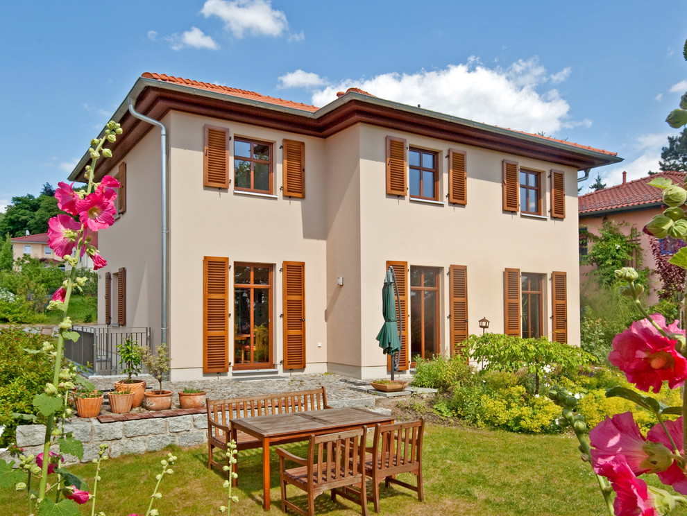 Cette image montre une grande façade de maison beige méditerranéenne en béton à deux étages et plus.