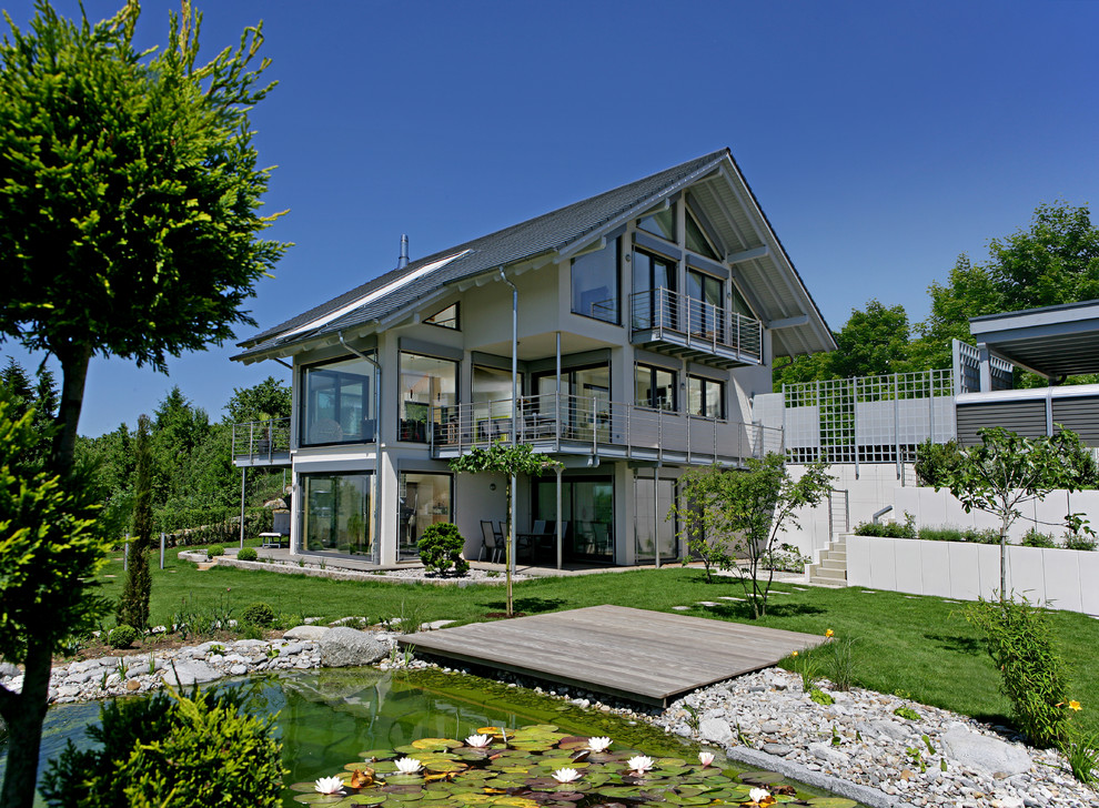 На фото: огромный, трехэтажный, серый дом в современном стиле с облицовкой из бетона и двускатной крышей