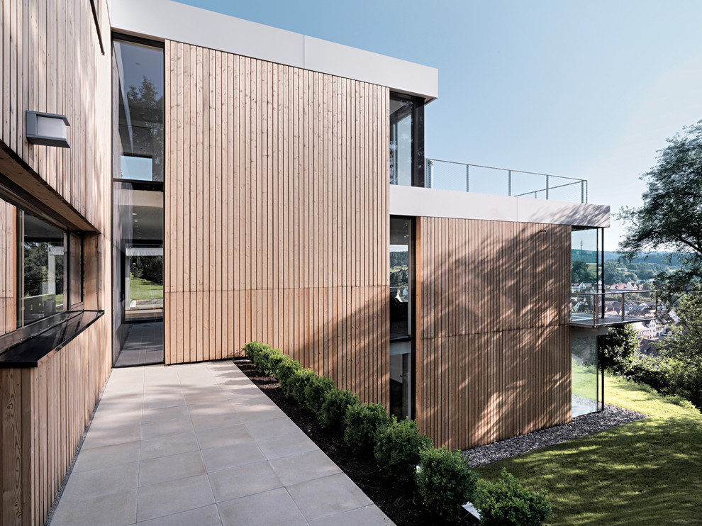 Design ideas for a large contemporary house exterior in Stuttgart with wood cladding and a flat roof.