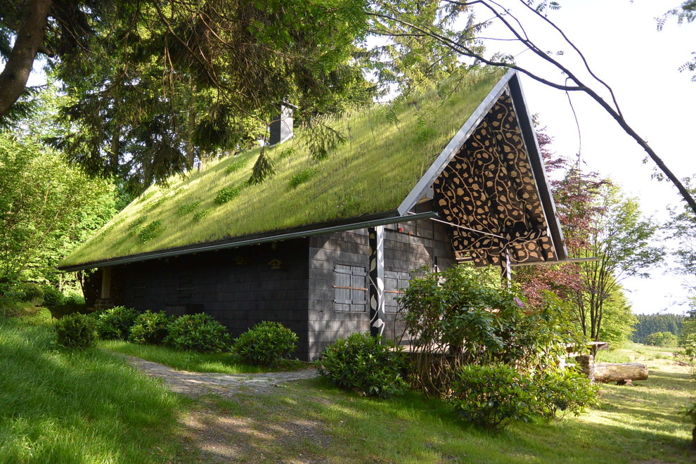 Ejemplo de fachada negra rural pequeña de una planta con revestimiento de madera y tejado a dos aguas