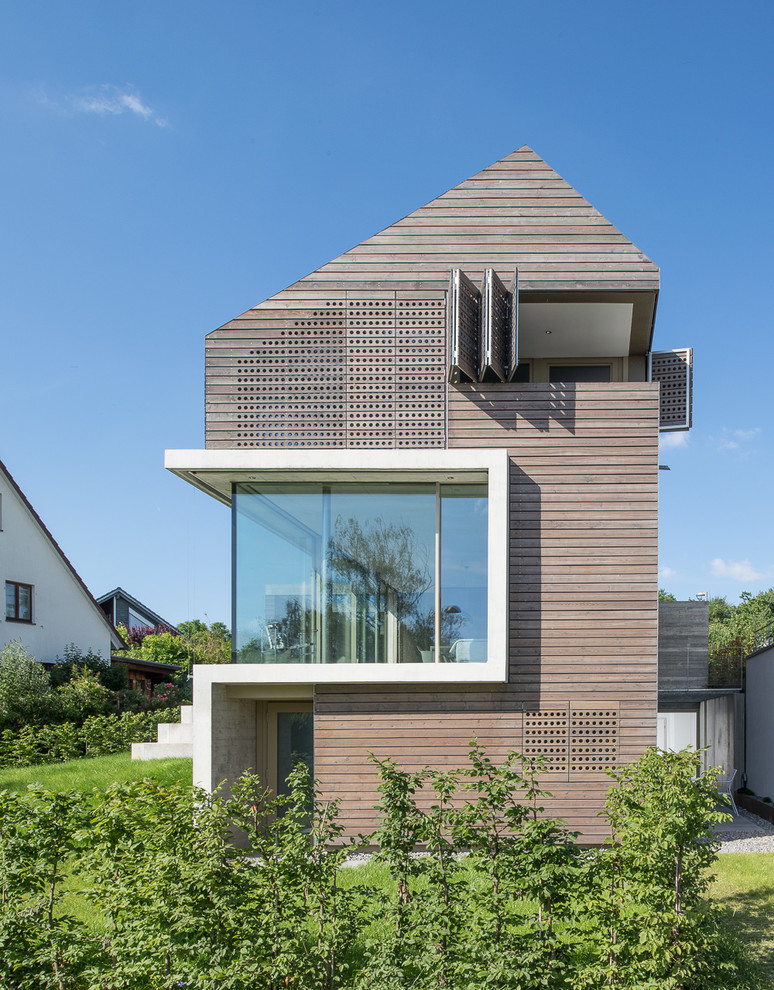 Inspiration for a large and brown contemporary house exterior in Stuttgart with three floors, wood cladding and a pitched roof.