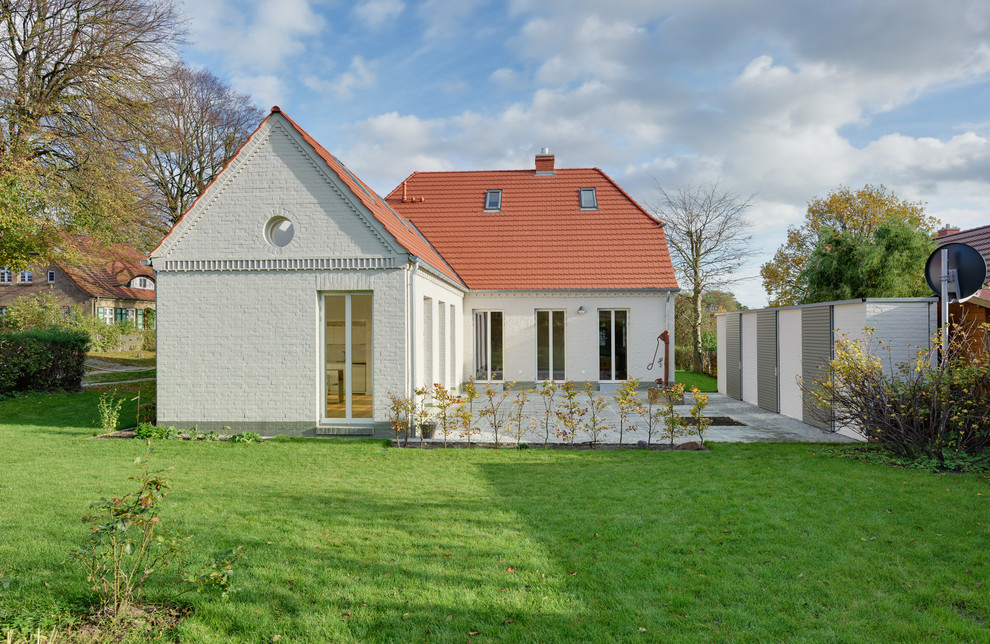Mid-sized elegant white one-story brick gable roof photo in Berlin
