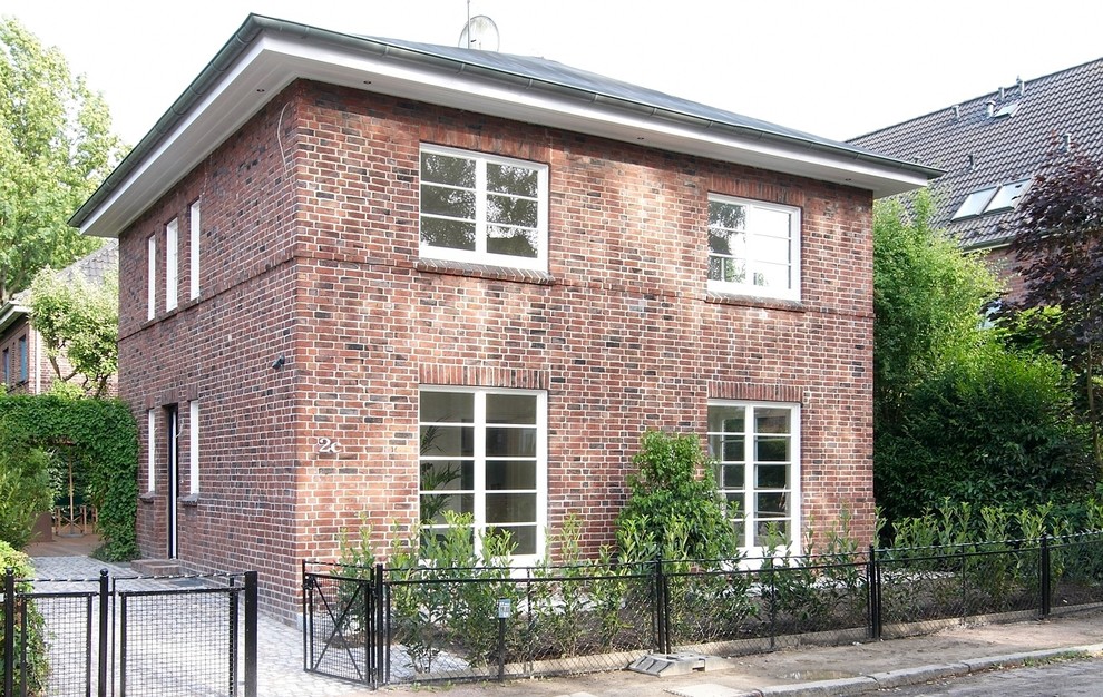 Стильный дизайн: двухэтажный, красный дом среднего размера в классическом стиле с облицовкой из камня и вальмовой крышей - последний тренд