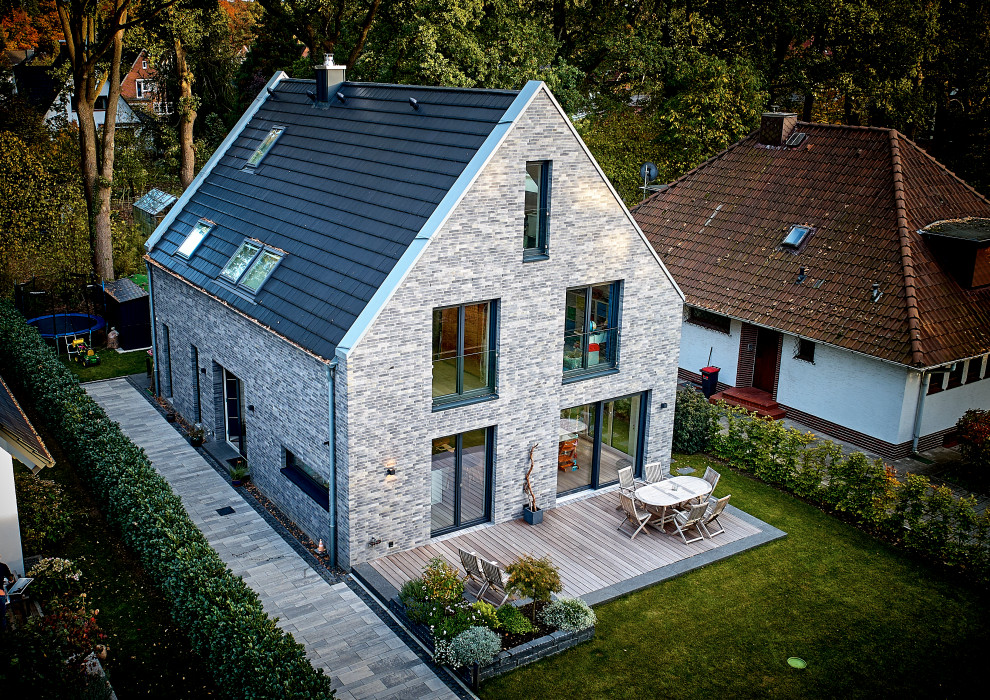 Ejemplo de fachada de casa contemporánea de tamaño medio de dos plantas con revestimiento de ladrillo, tejado a dos aguas y tejado de teja de barro