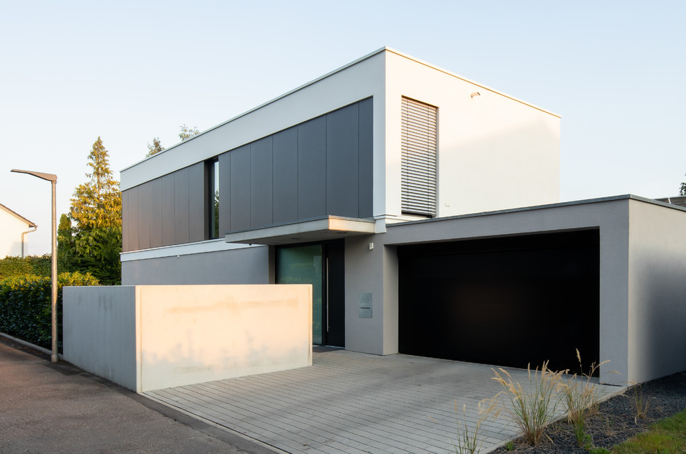 Cette image montre une façade de maison grise minimaliste de taille moyenne et à un étage avec un toit plat, un toit végétal et un revêtement mixte.