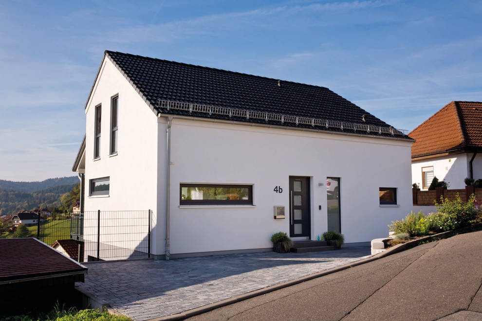 Пример оригинального дизайна: белый, маленький, трехэтажный дом в стиле неоклассика (современная классика) с облицовкой из цементной штукатурки и двускатной крышей для на участке и в саду