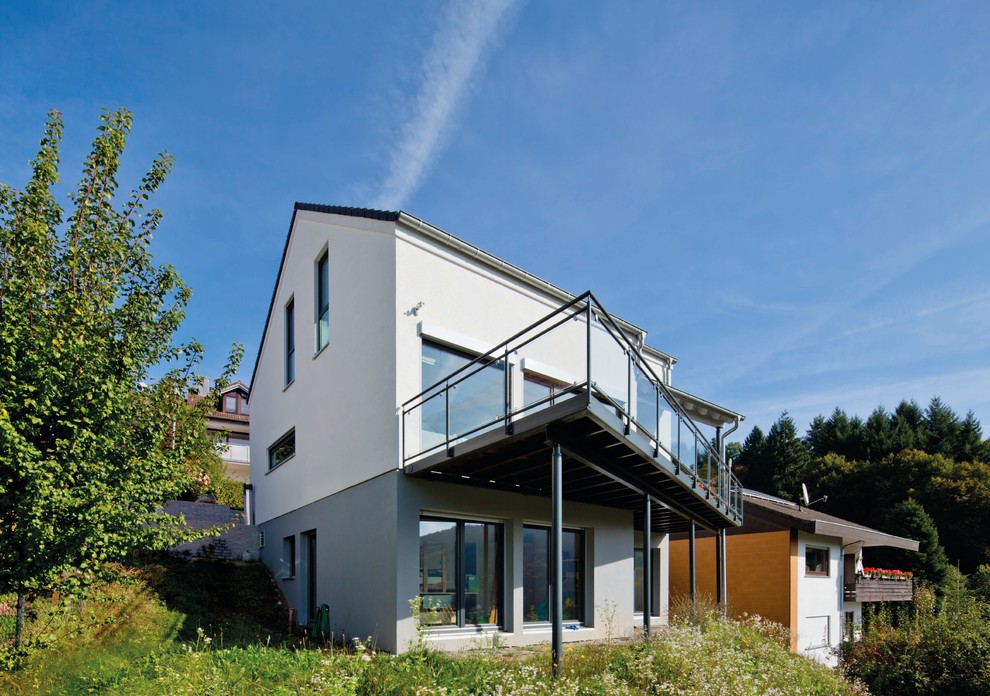Modelo de fachada de casa blanca contemporánea de tres plantas con revestimiento de estuco, tejado a dos aguas y tejado de teja de barro