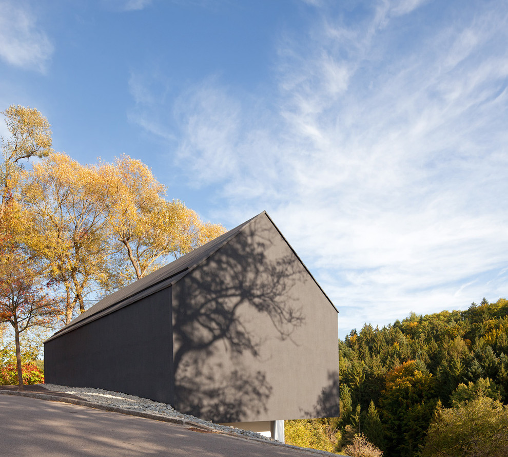Diseño de fachada de casa negra actual de tamaño medio de dos plantas con tejado a dos aguas y revestimientos combinados