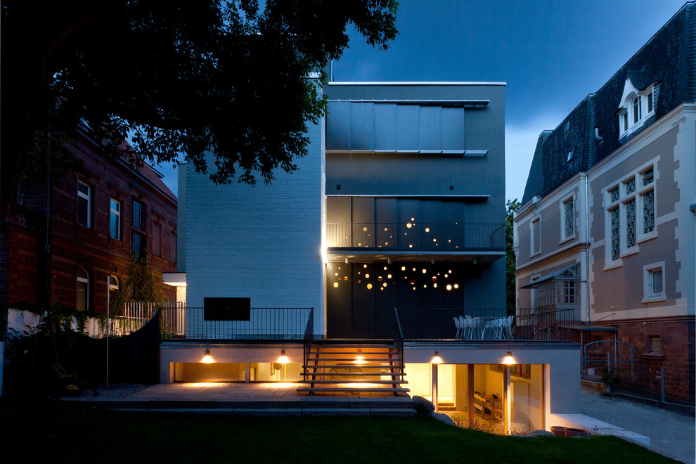 На фото: огромный, четырехэтажный, серый дом в современном стиле с облицовкой из цементной штукатурки и плоской крышей