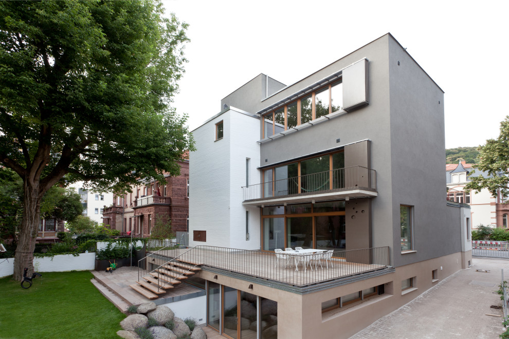 Cette image montre une très grande façade de maison grise design en stuc à trois étages et plus avec un toit plat.