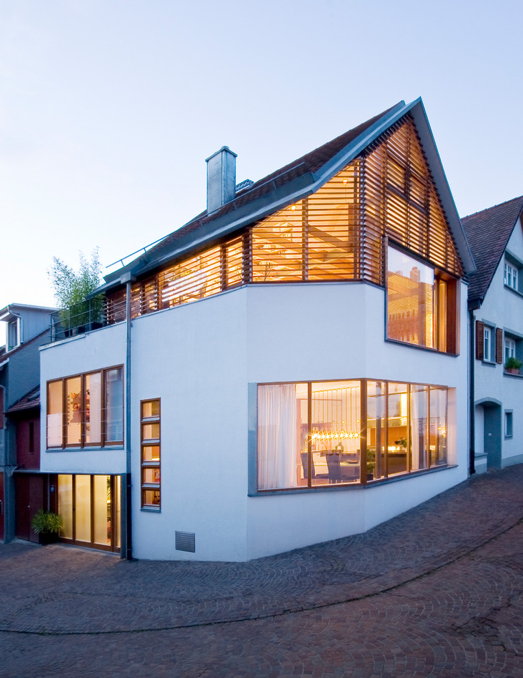 Свежая идея для дизайна: трехэтажный, белый дом среднего размера в современном стиле с двускатной крышей - отличное фото интерьера