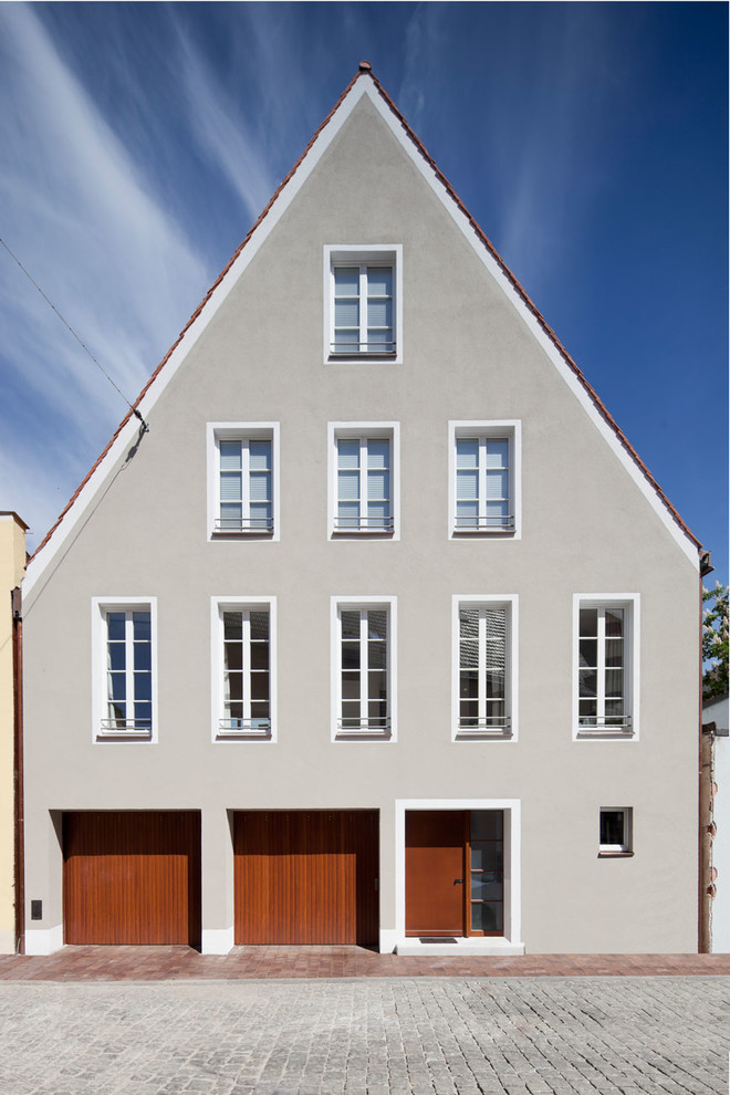Dreistöckiges, Mittelgroßes Klassisches Haus mit grauer Fassadenfarbe und Satteldach in München