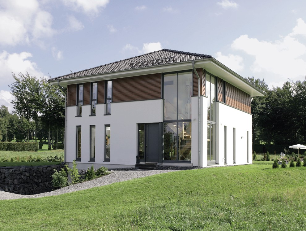 Foto de fachada blanca actual de tamaño medio de dos plantas con revestimientos combinados y tejado a cuatro aguas