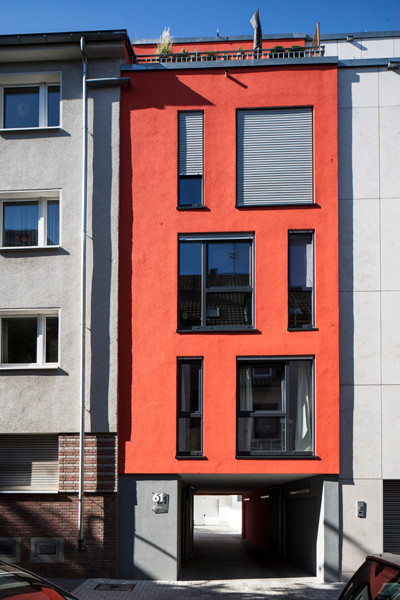 Kleines, Dreistöckiges Modernes Wohnung mit Putzfassade, roter Fassadenfarbe und Flachdach in Köln