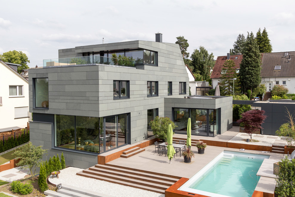 Dreistöckiges Modernes Einfamilienhaus mit Steinfassade, grauer Fassadenfarbe und Flachdach in Sonstige