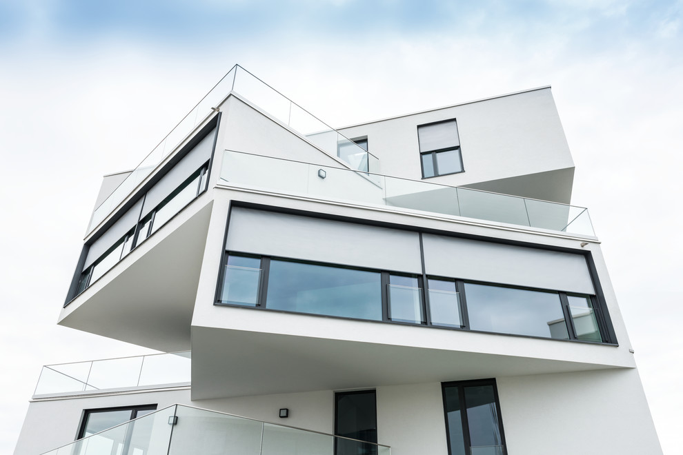 Großes, Dreistöckiges Modernes Haus mit weißer Fassadenfarbe und Flachdach in Berlin