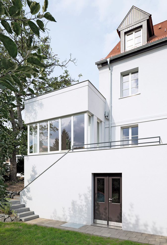 На фото: большой, трехэтажный, белый дом в современном стиле с двускатной крышей с