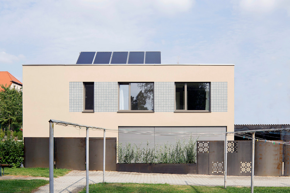 Mittelgroßes, Zweistöckiges Modernes Einfamilienhaus mit Putzfassade, beiger Fassadenfarbe und Flachdach in München