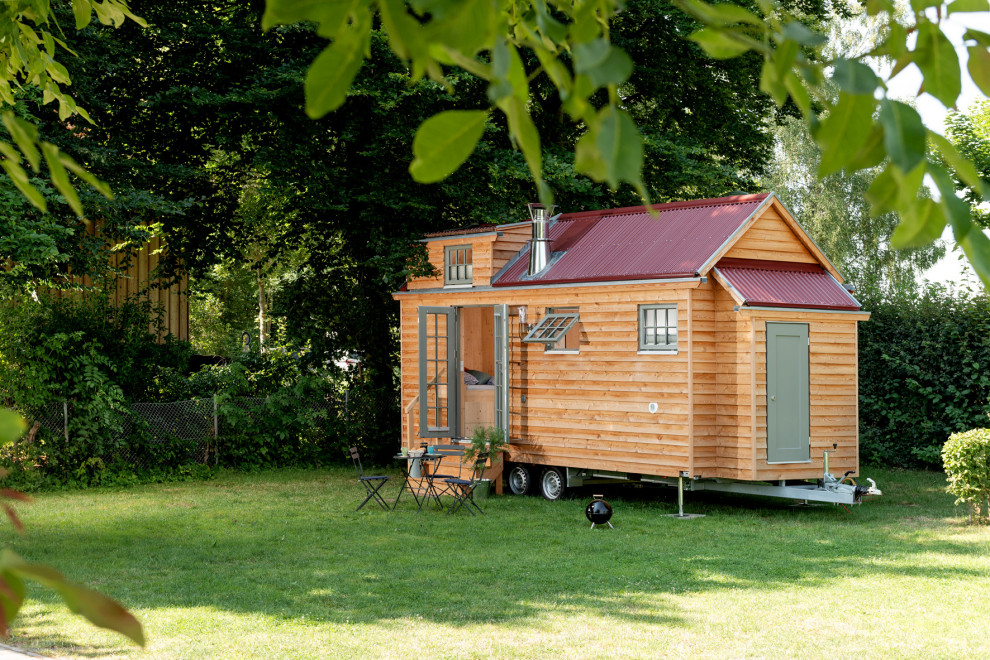 Cette image montre une petite façade de Tiny House marron chalet en bois à un étage avec un toit à deux pans et un toit en métal.
