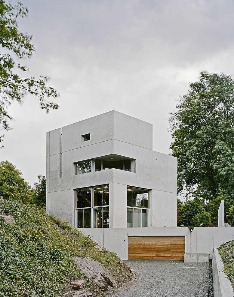 Gey and medium sized modern concrete house exterior in Stuttgart with three floors and a flat roof.