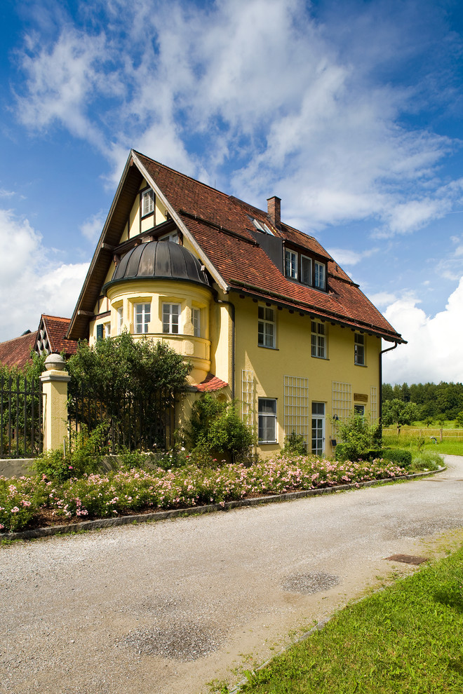 Photo of a medium sized and yellow classic house exterior in Munich with three floors and a pitched roof.