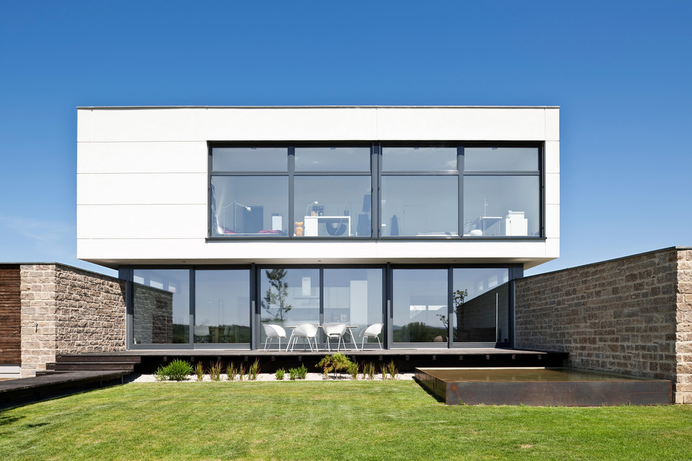 Пример оригинального дизайна: двухэтажный, белый дом в стиле модернизм с плоской крышей