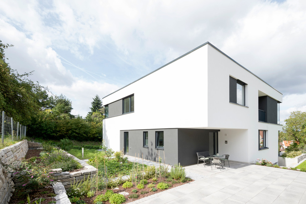 Modelo de fachada blanca contemporánea de tamaño medio de dos plantas con tejado plano y revestimiento de estuco