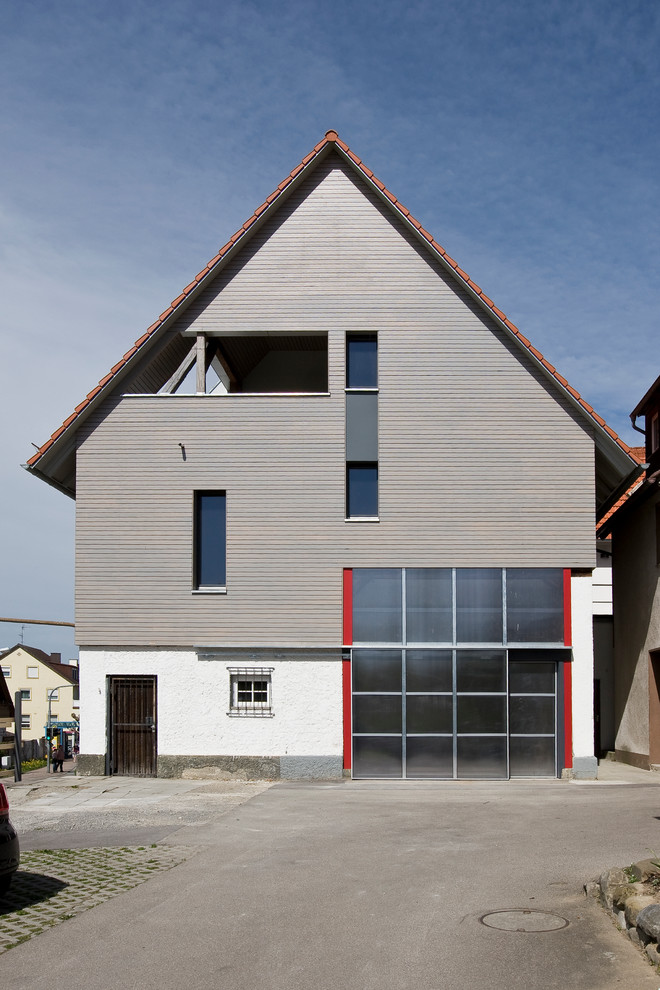 Modelo de fachada gris tradicional de tamaño medio de tres plantas con revestimiento de madera y tejado a dos aguas