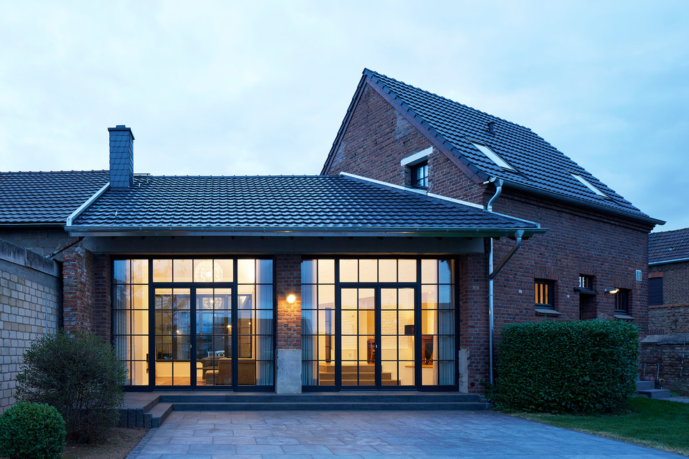 Photo of a large and red rustic two floor brick detached house in Cologne with a pitched roof and a tiled roof.