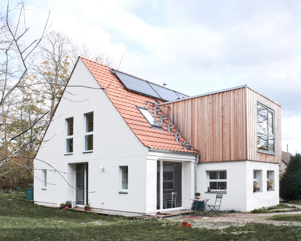Diseño de fachada de casa blanca rústica grande de dos plantas con revestimiento de estuco y tejado de teja de barro