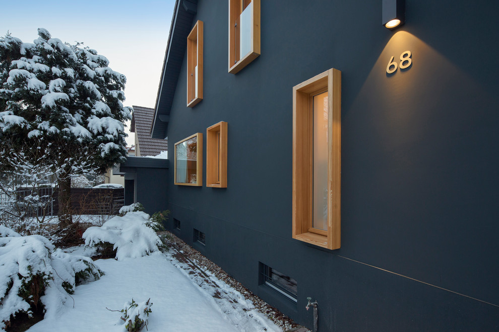 Cette photo montre une façade de maison bleue scandinave en stuc à un étage.